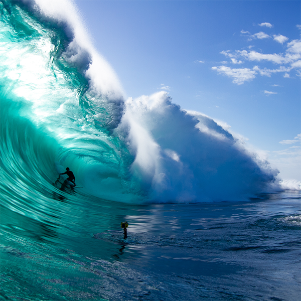 Person surfing on a large blue wave