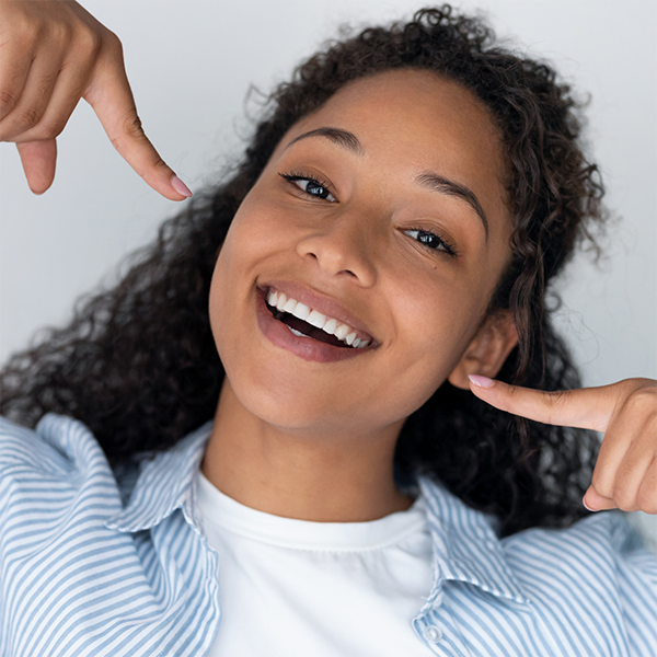 Young woman pointing to her smile