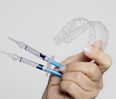 Hand holding a take-home teeth whitening kit