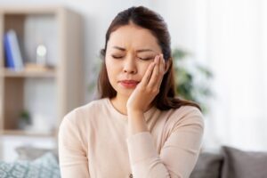 Woman clutching jaw from tooth sensitivity.